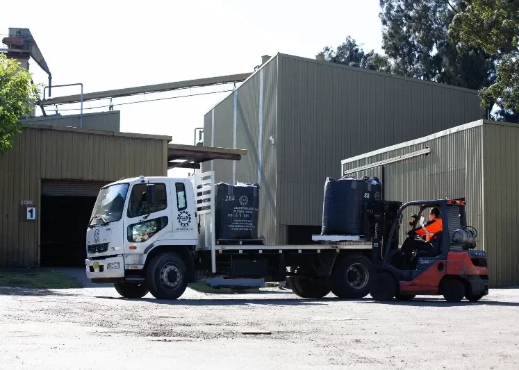 Worker using a forklift to get the sack of charcoal at the back of the truck