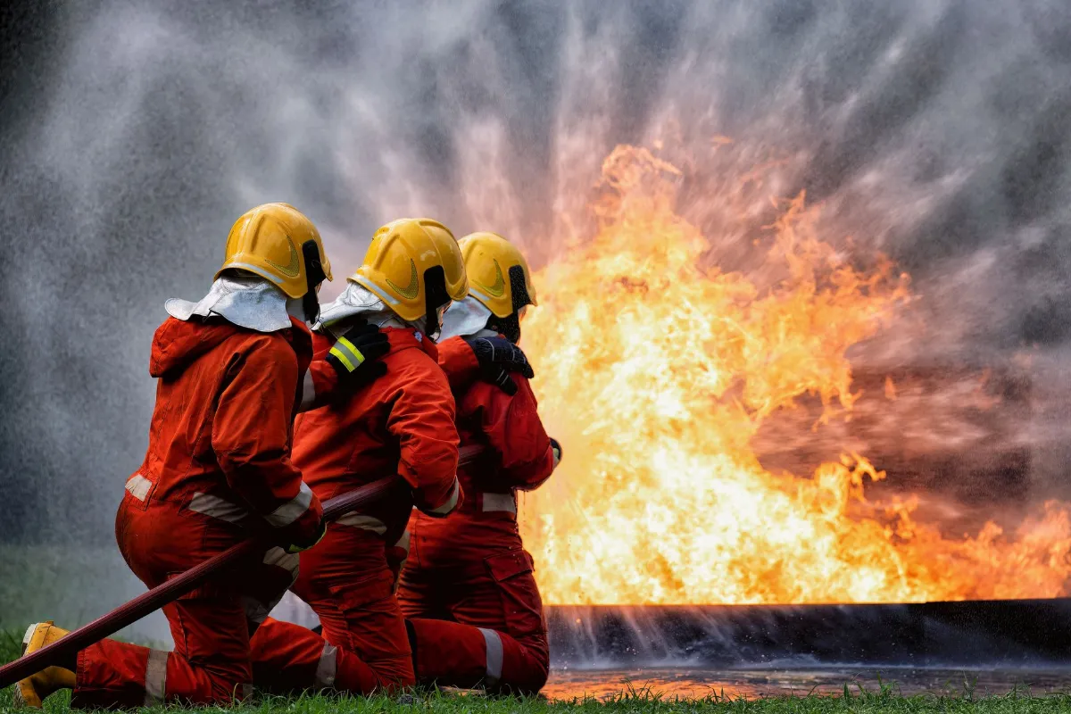 Fire Fighters in training holding using hose to stop fire